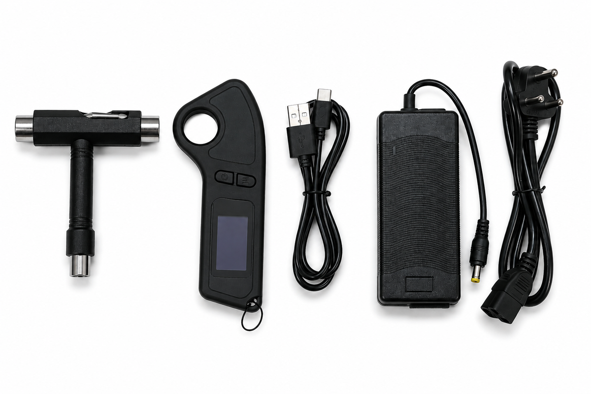 A black handheld electronic device with a small screen, shown with several included accessories on a white background: a T-shaped metal tool, a USB cable, a rectangular power adapter, and a wall plug.