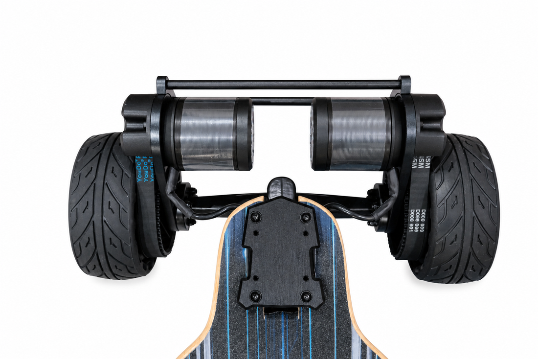 Close-up rear view of a longboard skateboard with dual rear wheels, black tires, and a black metal frame, shown against a plain white background.